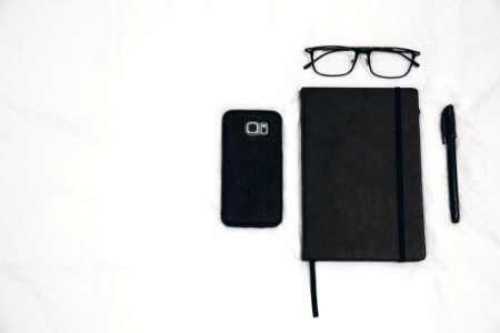 Black Smartphone Beside Planner And Eyeglasses And Pen
