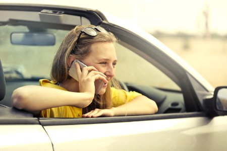 Blonde-haired Woman In Yellow T-shirt Wearing Black Sunglasses Holding Silver Smartphone