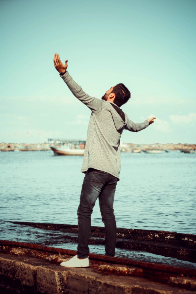 Man In GrEy Hoodie Standing On Grey Pavement Near Sea