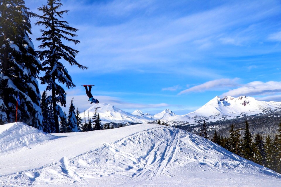 Person Doing Tricks In Mid Air Using Snowboard On Snowfield Mountain