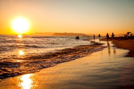 Group Of People Walking At The Shoreline During Golden Hour