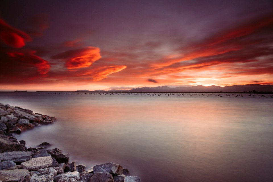 Landscape Photography Of Rocks Near Body Of Water During Sunset