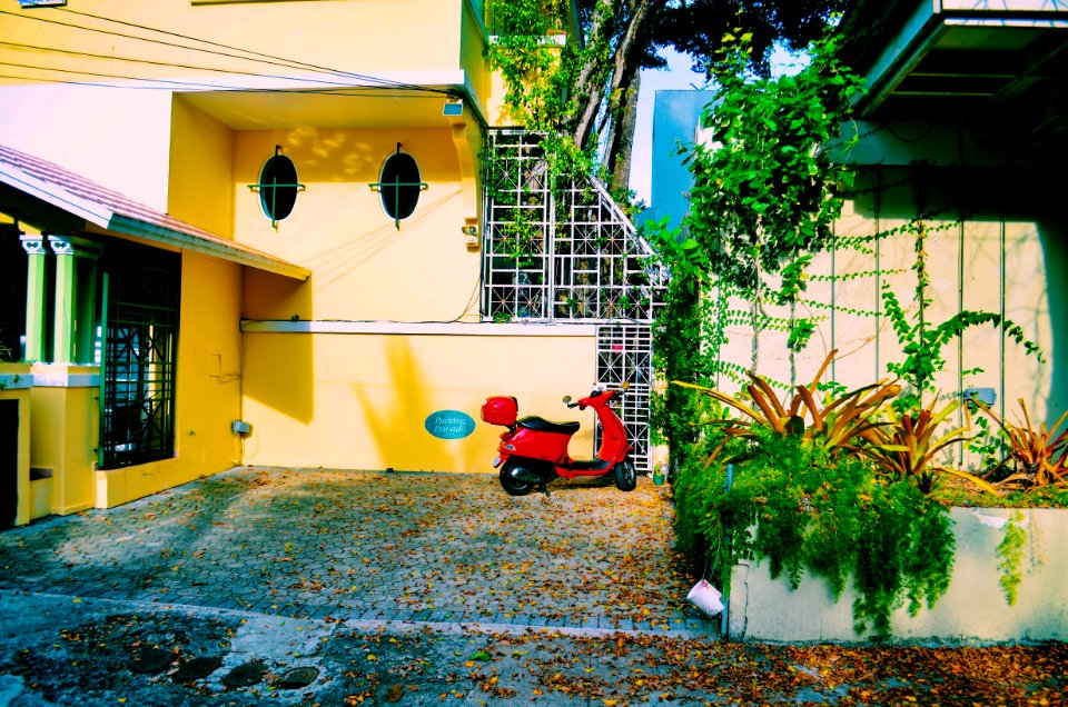Red Motor Scooter Parked Beside The Beige Concrete Wall