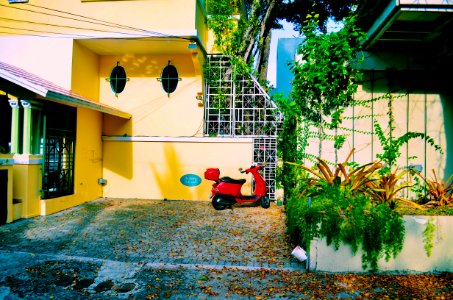 Red Motor Scooter Parked Beside The Beige Concrete Wall photo