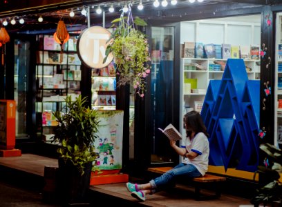 Woman Sitting Down On Bench And Reading Infront Of Store photo