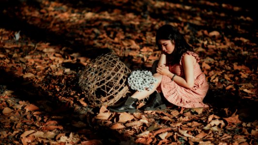 Woman Wearing Red Dress Sitting On Brown Ground With Woven Brown Basket