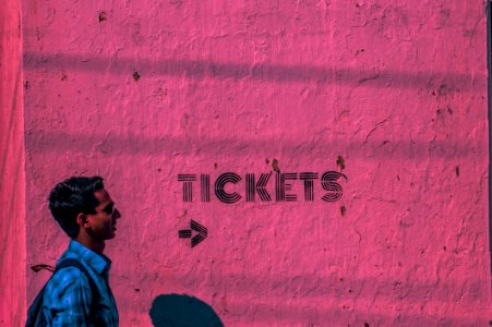 Man Wearing Blue Sports Shirt And Backpack Passing Through Pink Wall