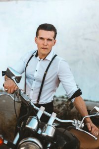 Man In White Dress Shirt With Suspenders Holding Black Motorcycle photo