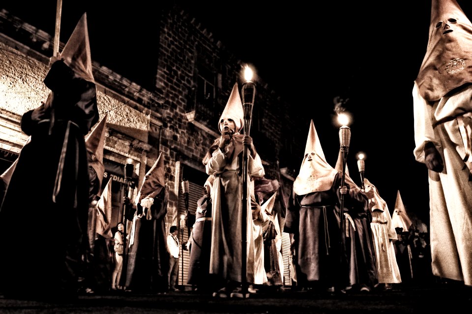 Group Of People In White Hood Holding Torch On Street