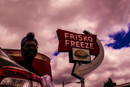 Man In Baseball Cap Near Frisko Freeze Signage