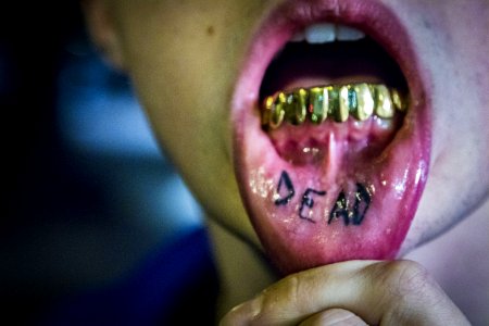 Photography Of Man Showing Tattoo And Gold Teeth