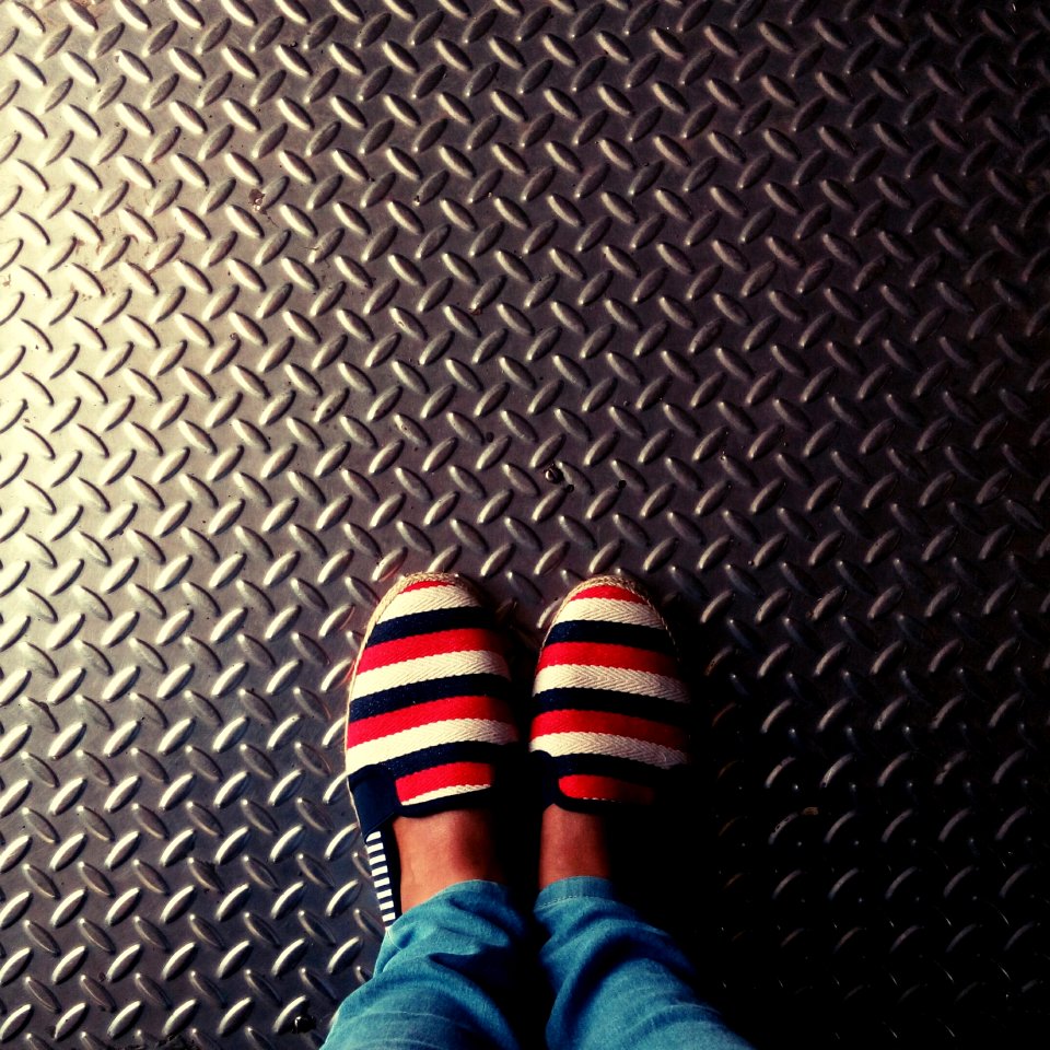 Person Wearing Red-and-multicolored Slip-on Shoes Standing On Gray Metallic Diamond Plate