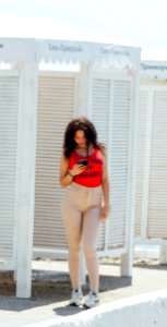 Woman In Red Tank Top And Gray High-waist Jeans Standing Near Wooden Cabinet