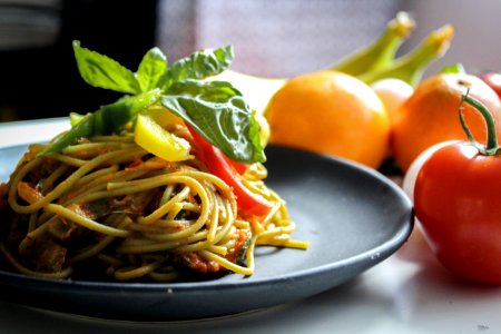 Pasta With Vegetable Dish On Gray Plate Beside Tomato Fruit On White Table