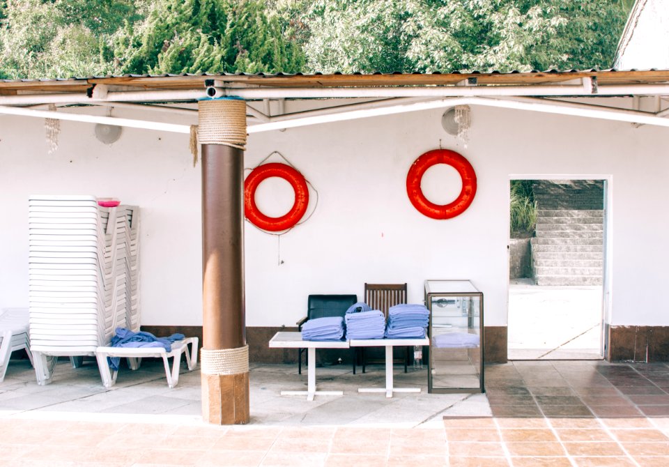 Pile Of Blue Garment On Top Of Two White Pedestal Tables Near Two Chairs