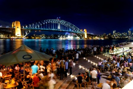 People Sitting And Standing Near Bridge During Nighttime photo