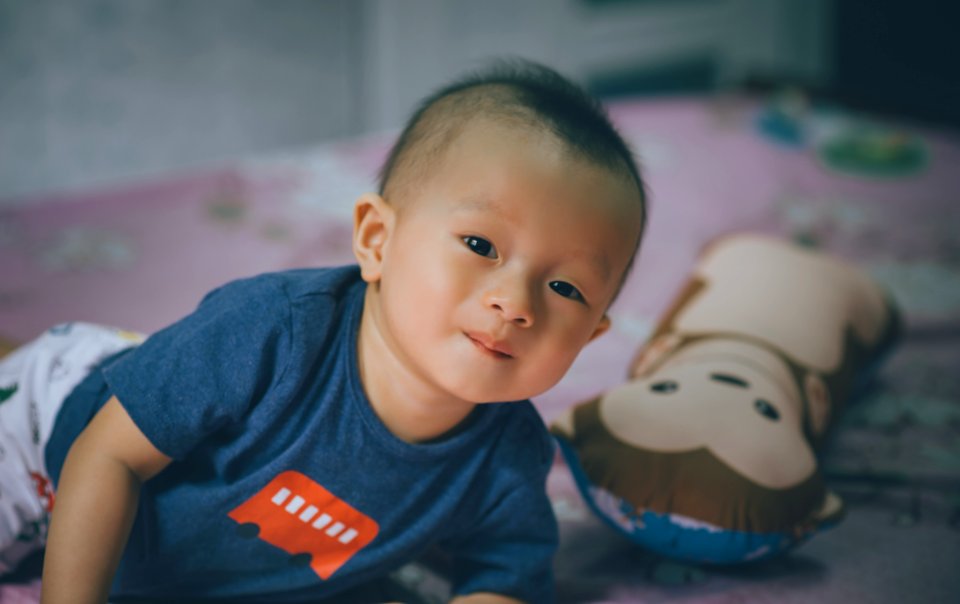 Close-Up Photography Of Baby Lying On The Bed Near Bolster Pillow photo