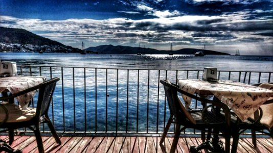 White Table With Two Armchair Set Near Body Of Water And Mountain photo