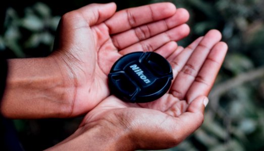 Black Nikon Camera Lens Cover On Left And Right Human Palms photo