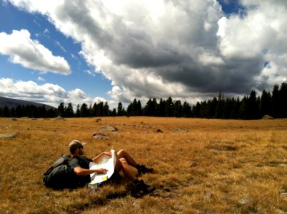 Man In Black Shirt With Black Backpack Lying On Brown Grass Photo