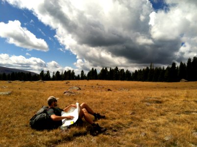 Man In Black Shirt With Black Backpack Lying On Brown Grass Photo photo