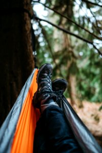 Person Wearing Pair Of Black Hiking Shoes Lying On Orange And Gray Hammock photo