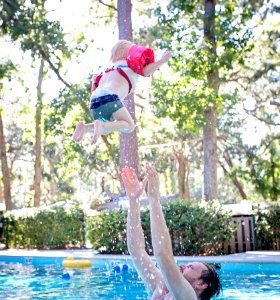 Photography Of Man On Swimming Pool Tossing Toddler Above Pool
