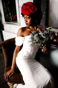 Woman Wearing White Off-shoulder Bodycon Dress Holding Flower Arrangement In Vase