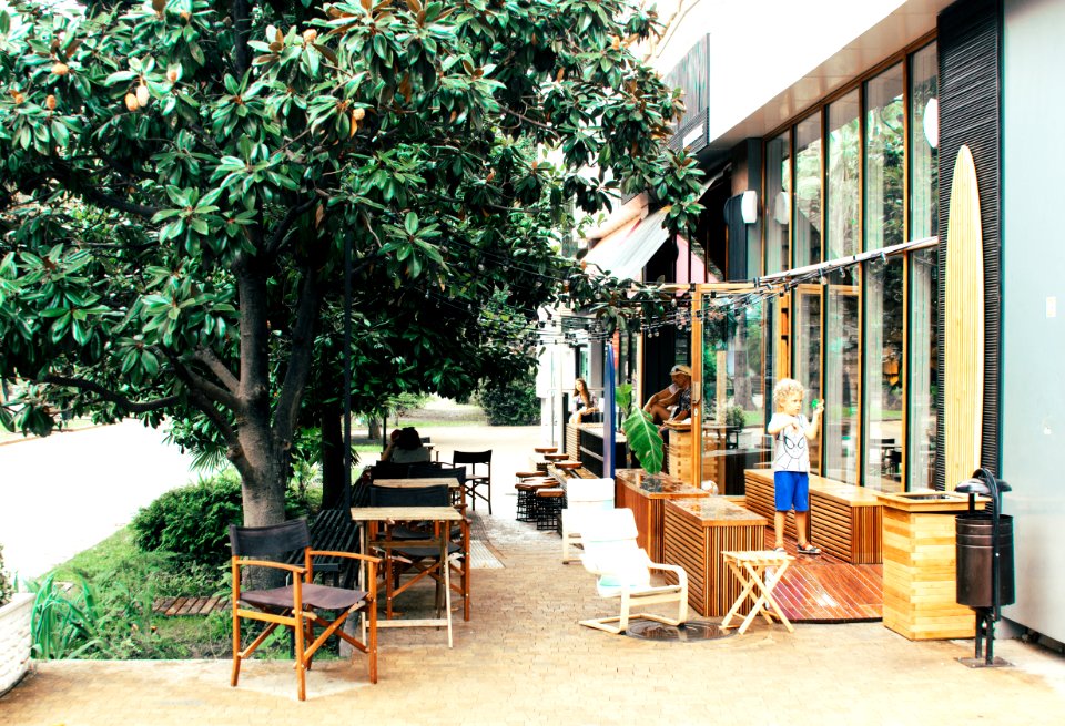 Child Outside Building Near Wooden Furniture And Tree