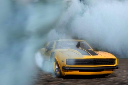 Classic Yellow And Black Sports Car Drifting On Road With Smoke photo