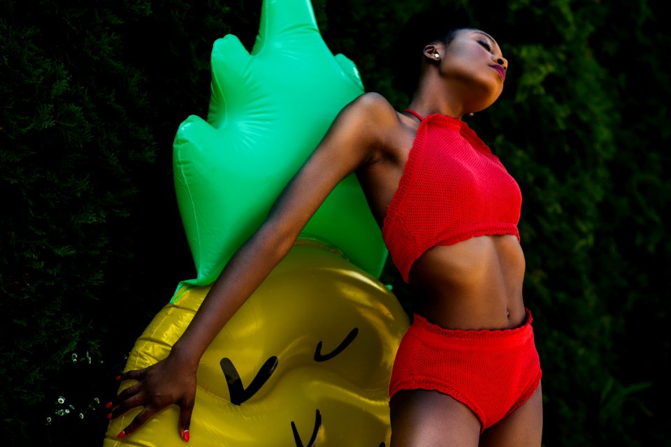 Woman Wearing Red Top And Bottoms Leaning On Yellow And Green Inflatable Standee
