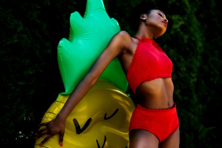 Woman Wearing Red Top And Bottoms Leaning On Yellow And Green Inflatable Standee photo