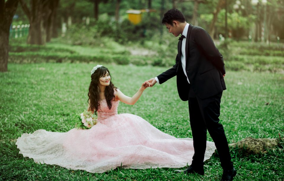 Man In 2-piece Suit Holding Woman In Peach-colored Wedding Gown White Holding Her Flower Bouquet photo