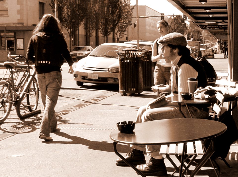 Man In Black And White Long-sleeved Shirt Sits On Brown Wooden Chair Facing Road