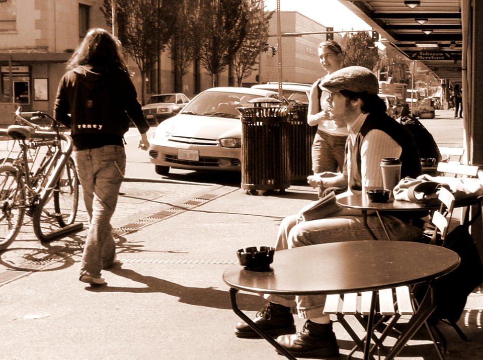 Man In Black And White Long-sleeved Shirt Sits On Brown Wooden Chair Facing Road photo