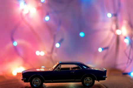 Selective Focus Photography Of Classic Blue Coupe Die-cast Model In Front Of String Lights On Table photo