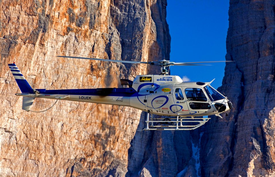 Selective Photograph Of White Helicopter Near Brown Mountains