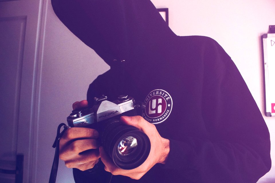 Man Holding Black And Gray Dslr Camera Inside White Wall Paint Room
