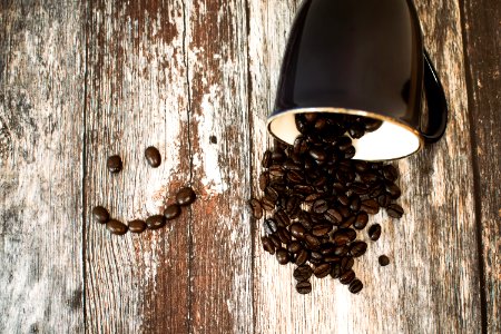 Black Ceramic Cup With Coffee Beans All On Brown Wooden Surface photo