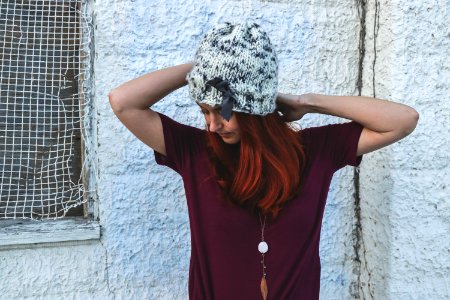 Woman In White And Black Knit Cap Posing Near White Wall photo