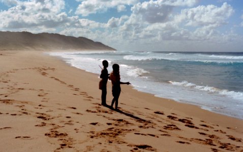 Two Children Stands On Shore Near Ocean At Daytime