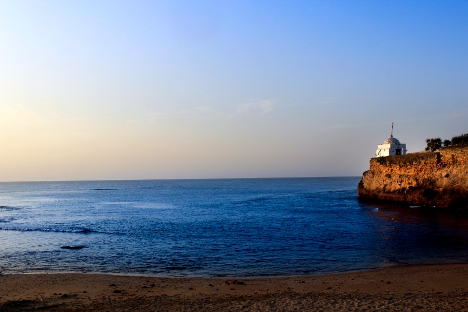 White Lighthouse Near Sea Under Blue Sky photo