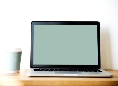 Grey And Black Laptop Beside White And Teal Coffee Cup photo