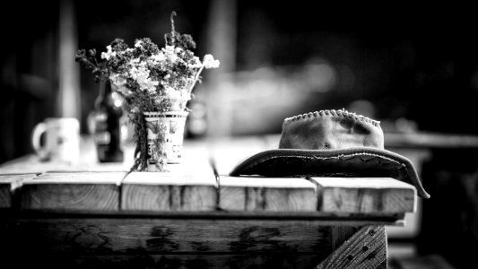 Grayscale Photography Of Hat On Wooden Table photo