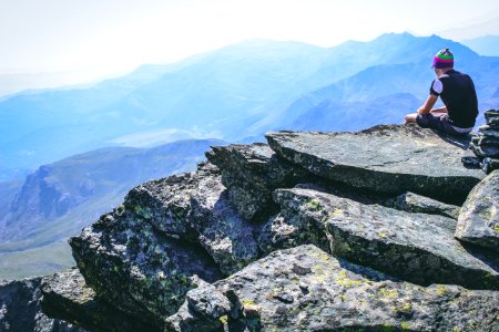 Photography Of A Man Sitting On Rock