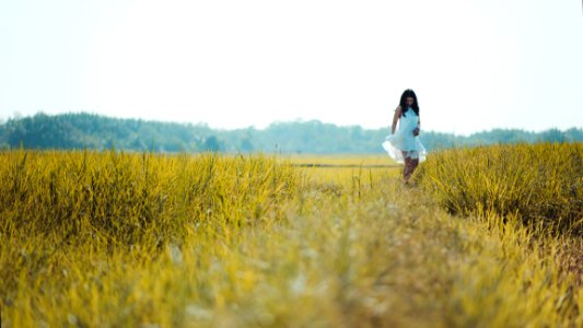 Depth Of Field Photography Of Woman Wearing White Sleeveless Dress Standing On Green Grass Field photo
