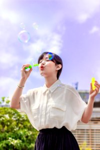 Photo Of Woman In White Blouse Playing With Bubbles photo