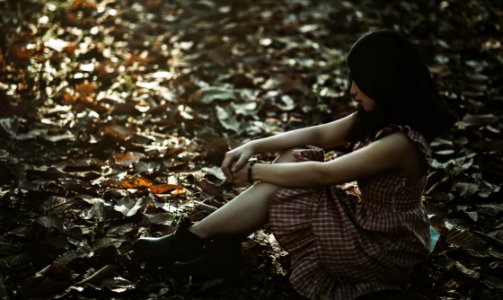 Photo Of A Woman Sitting On The Ground Covered With Dried Leaves