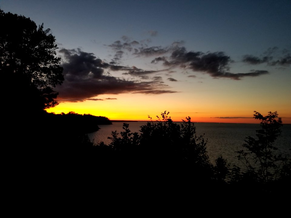 Body Of Water Near Trees Under Orange Sunset