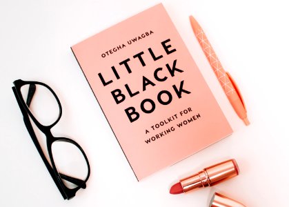 Little Black Book Surrounded With Pink Click Pen Red Lipstick And Black Wayfarer Eyeglasses photo